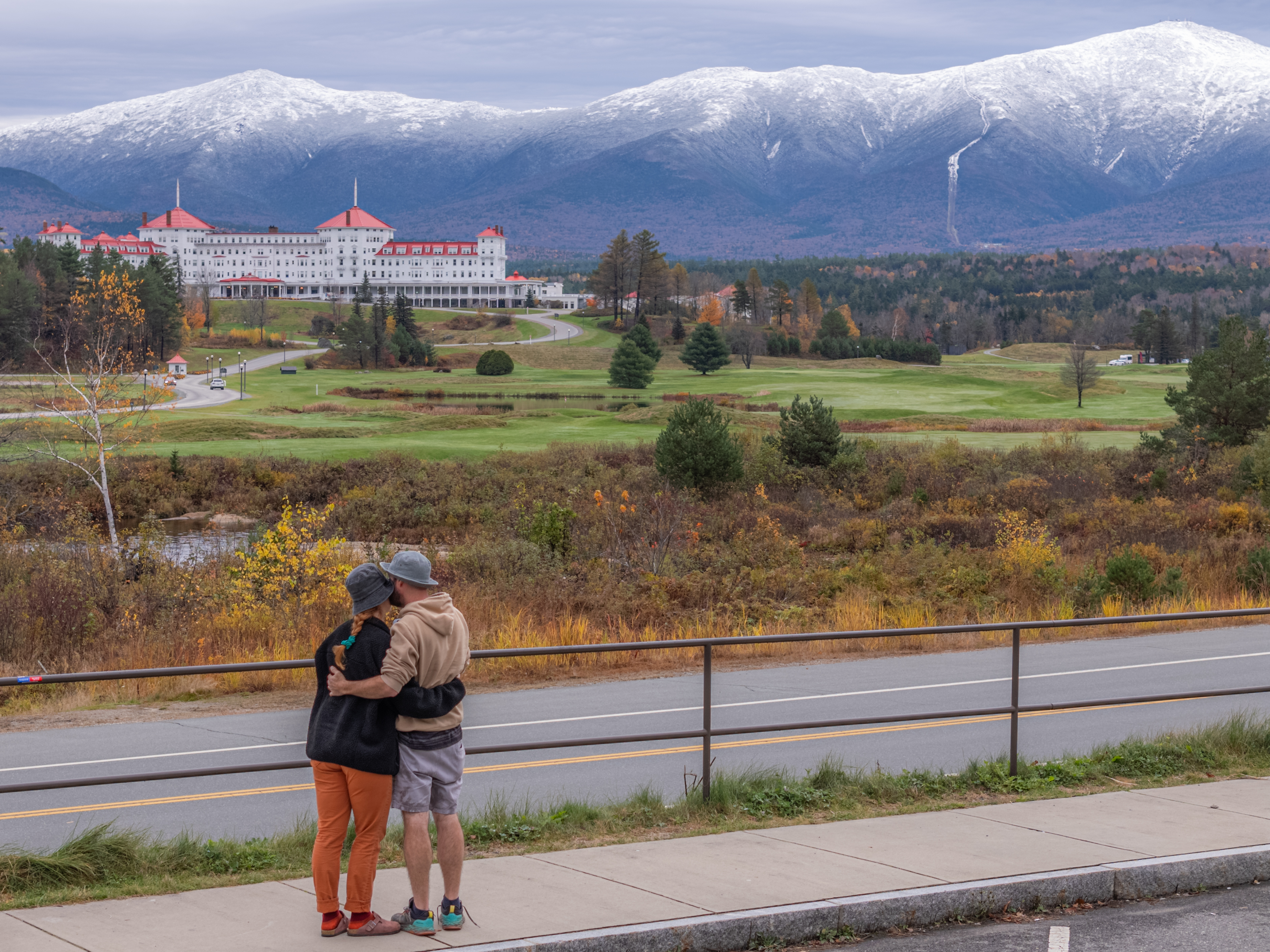 A couple looking out toward the Mount Washington Hotel below the snow-dusted Presidential Range